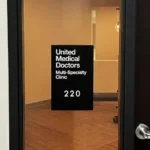 "United Medical Doctors" Wayfinding ADA Room ID Placard ADA-compliant room identification placard installed on interior glass window.