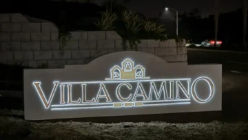 Villa Camino Monument – Oceanside, CA (Solar Powered) Illuminated “Villa Camino” monument sign at night, featuring three decorative arches with bell motifs, set against a landscaped stone wall and street backdrop in Oceanside, California. The sign is solar powered.