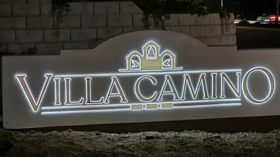 Villa Camino Monument – Oceanside, CA (Solar Powered) Illuminated “Villa Camino” monument sign at night, featuring three decorative arches with bell motifs, set against a landscaped stone wall and street backdrop in Oceanside, California. The sign is solar powered.