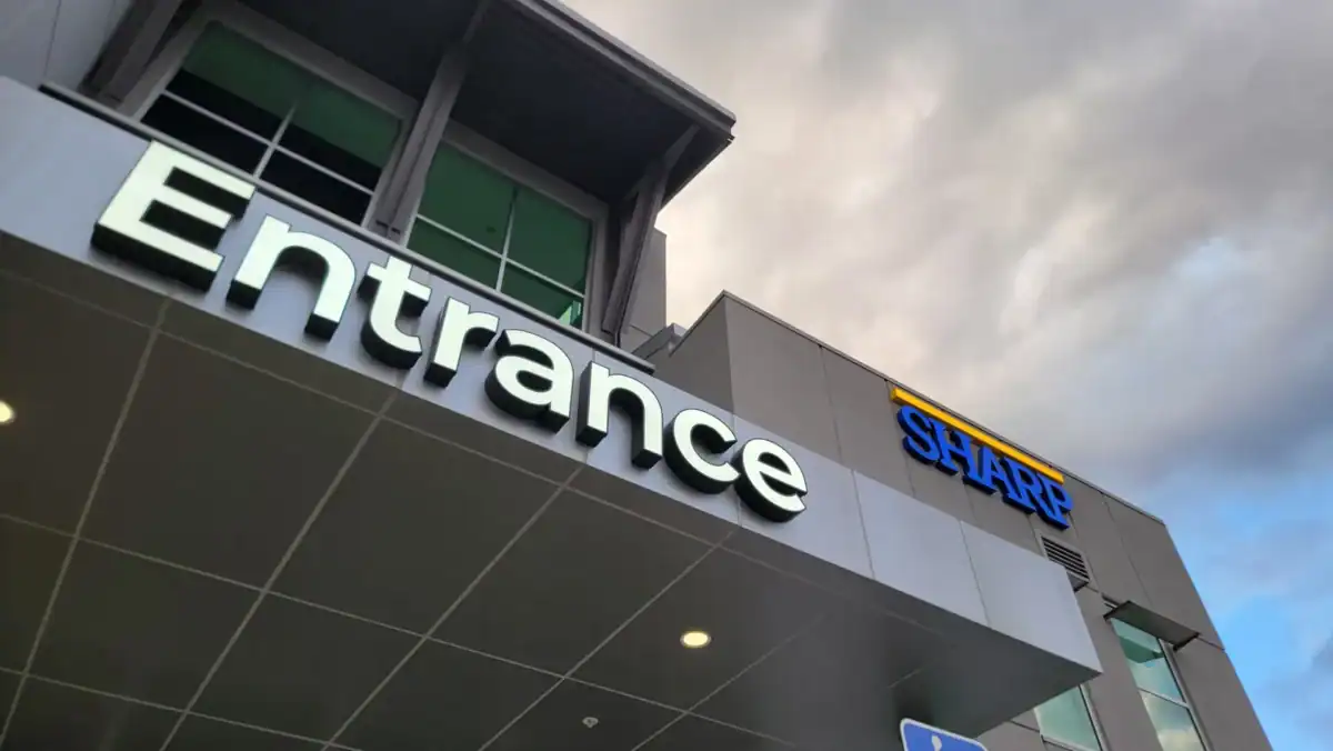 Illuminated channel letter signs for "Entrance" and "SHARP" on a modern medical building in San Diego, CA.