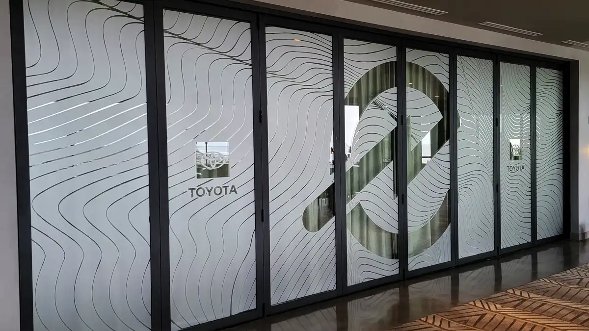 Toyota Frosted Glass Vinyl Wave Pattern Event Encinitas CA Custom frosted glass vinyl film installed on a wall of folding glass doors for a Toyota/Toyoda event in Encinitas, featuring a large abstract wave pattern and corporate logos.